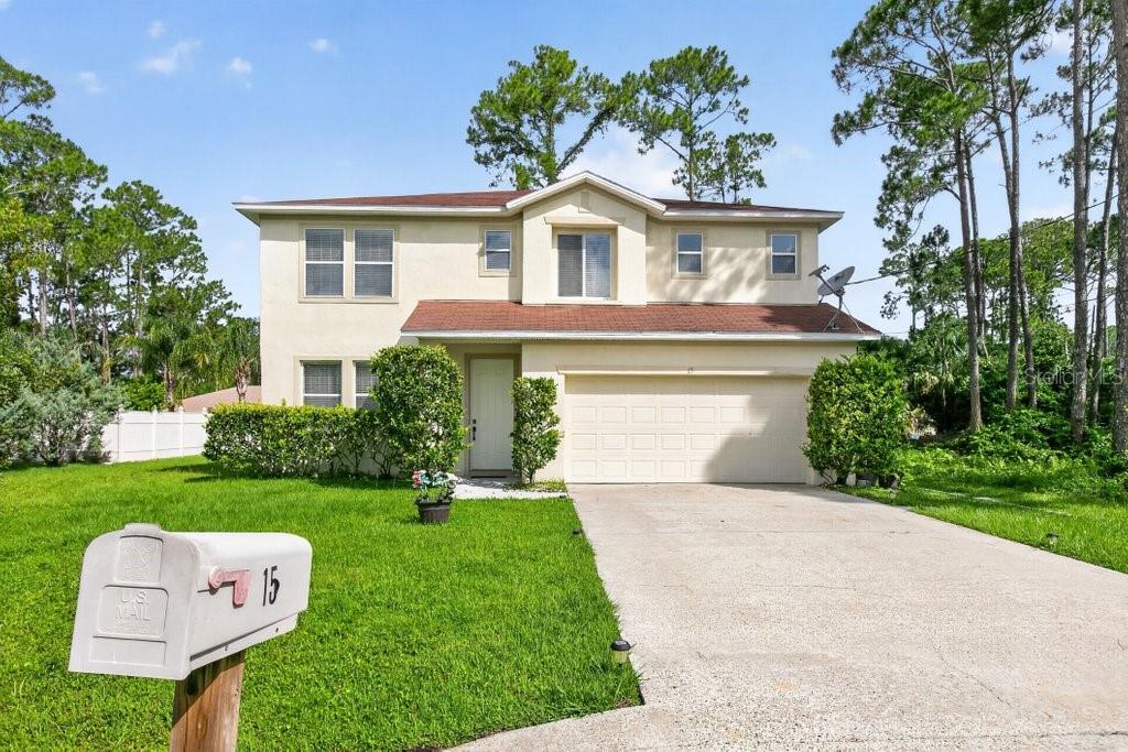 A two-story house with a beige stucco exterior, a shingled roof, and a concrete driveway — 15 RYKER LANE, PALM COAST, FL