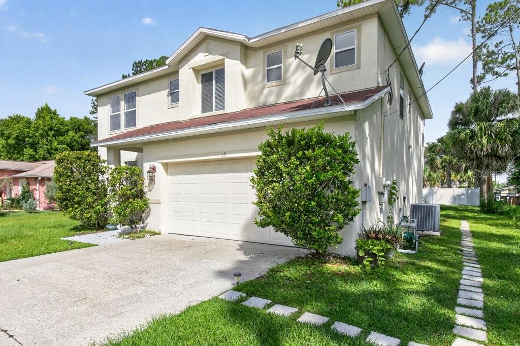 A two-story house with a beige stucco exterior, a single-car garage, and a concrete driveway — 15 RYKER LANE, PALM COAST, FL