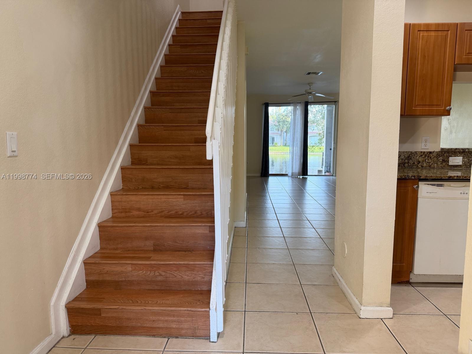 A staircase with wood treads stands beside a tiled living area with a water view — 8246 SW 27th St # 103, Miramar FL 33025, MIRAMAR, FL