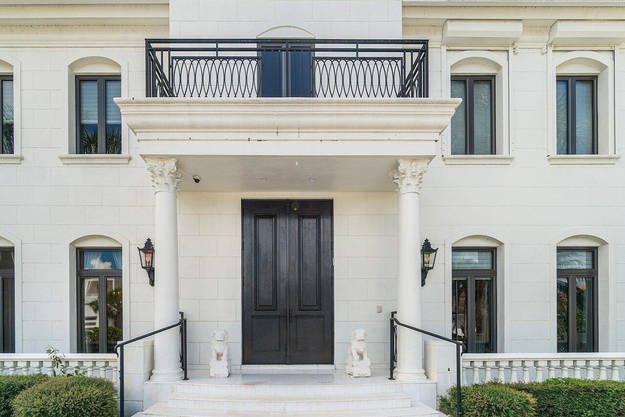 A white stone building exterior features a black double door, columns, and a balcony — 7172 Valencia Drive, Boca Raton FL 33433, BOCA RATON, FL