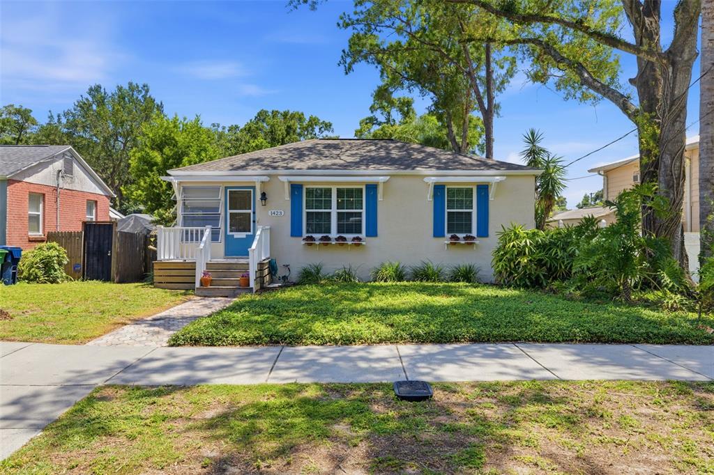 A single-story house with a light-colored exterior, blue shutters, and a small front porch — 1423 E HENRY AVENUE, TAMPA, FL
