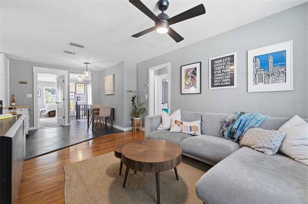 A living room features a gray sectional sofa, a round wooden coffee table, and hardwood floors — 1423 E HENRY AVENUE, TAMPA, FL