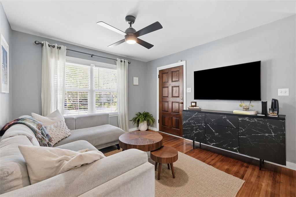 A living room features a grey sectional sofa, a black marble console, and a ceiling fan — 1423 E HENRY AVENUE, TAMPA, FL