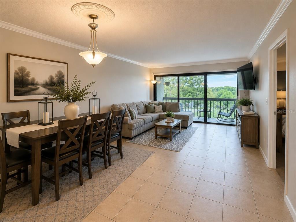 An open-concept living and dining area features tile flooring, a sectional sofa, and balcony access — 1068 LOTUS PARKWAY UNIT 836, ALTAMONTE SPRINGS, FL