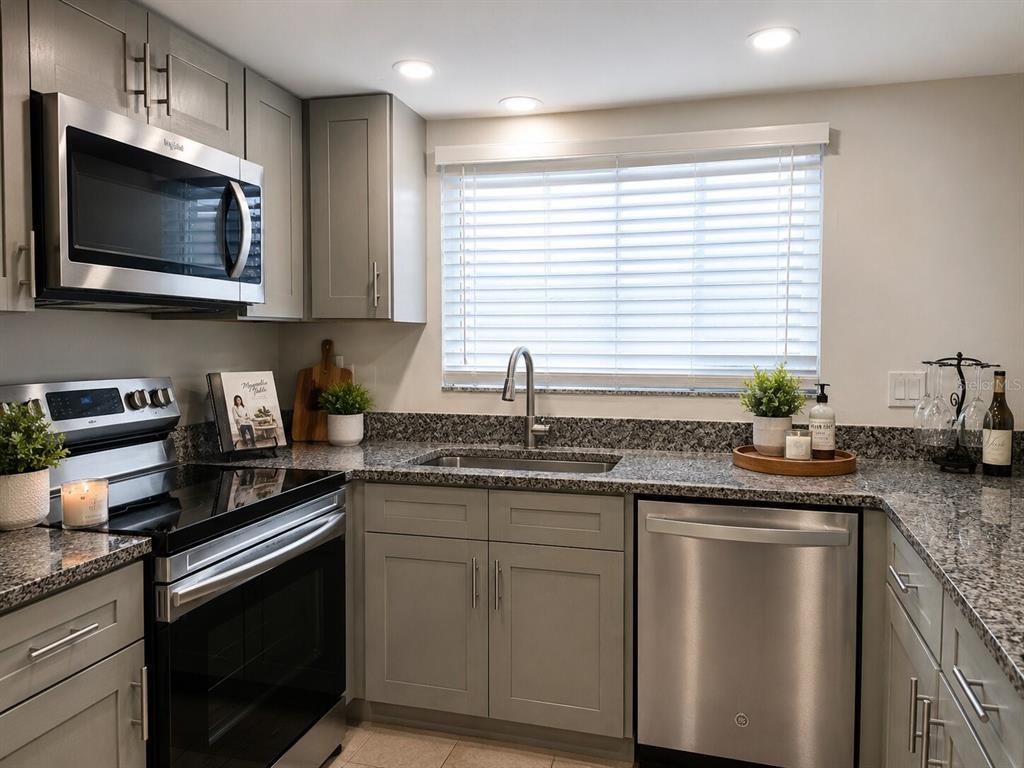 A kitchen featuring gray cabinets, granite countertops, stainless steel appliances, and a window with blinds — 1068 LOTUS PARKWAY UNIT 836, ALTAMONTE SPRINGS, FL