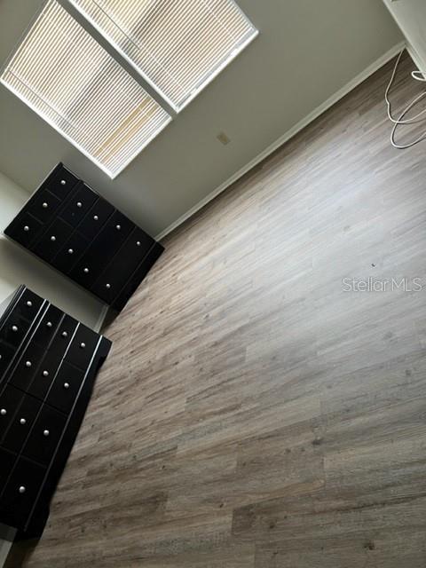 A bedroom features wood-look flooring, two black dressers, and windows with white blinds — 127 CAMPHOR CIRCLE UNIT D, OLDSMAR, FL