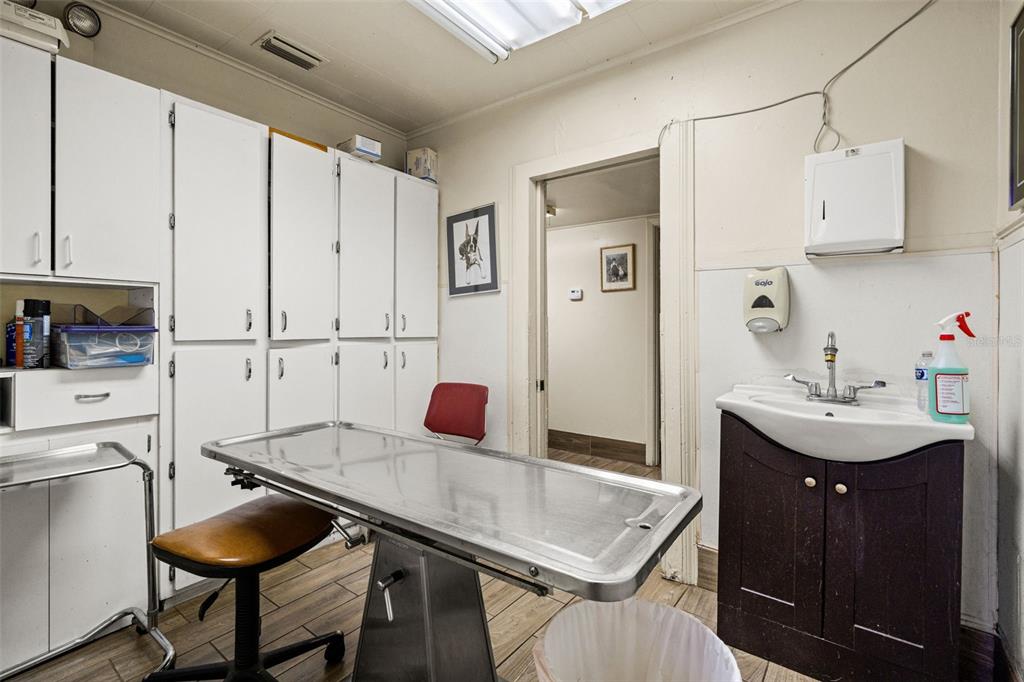 A veterinary exam room features a stainless steel table, a sink, and white storage cabinets — 6603 N FLORIDA AVENUE, TAMPA, FL