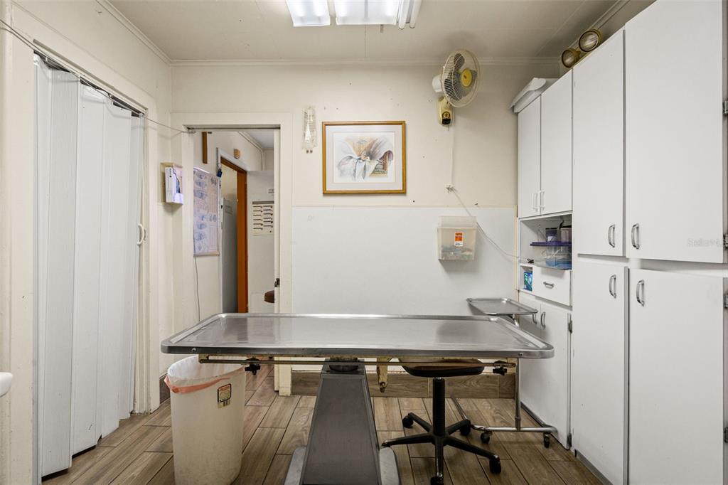 A clinical examination room features a metal table, white cabinets, and wood-look tile flooring — 6603 N FLORIDA AVENUE, TAMPA, FL