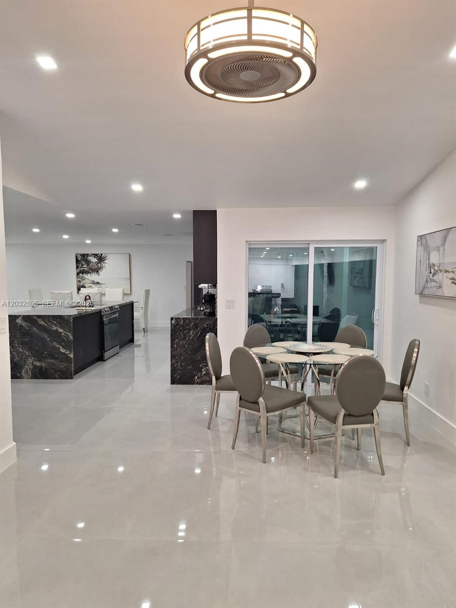 A dining area with a glass table and gray chairs sits beside a modern kitchen — 4440 SW 14 pl, Cape Coral FL 339914, CAPE CORAL, FL