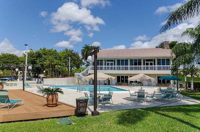 A swimming pool sits in front of a two-story building with a balcony and umbrellas — 7956 Camino Cir # A4, Miami FL 33143, MIAMI, FL