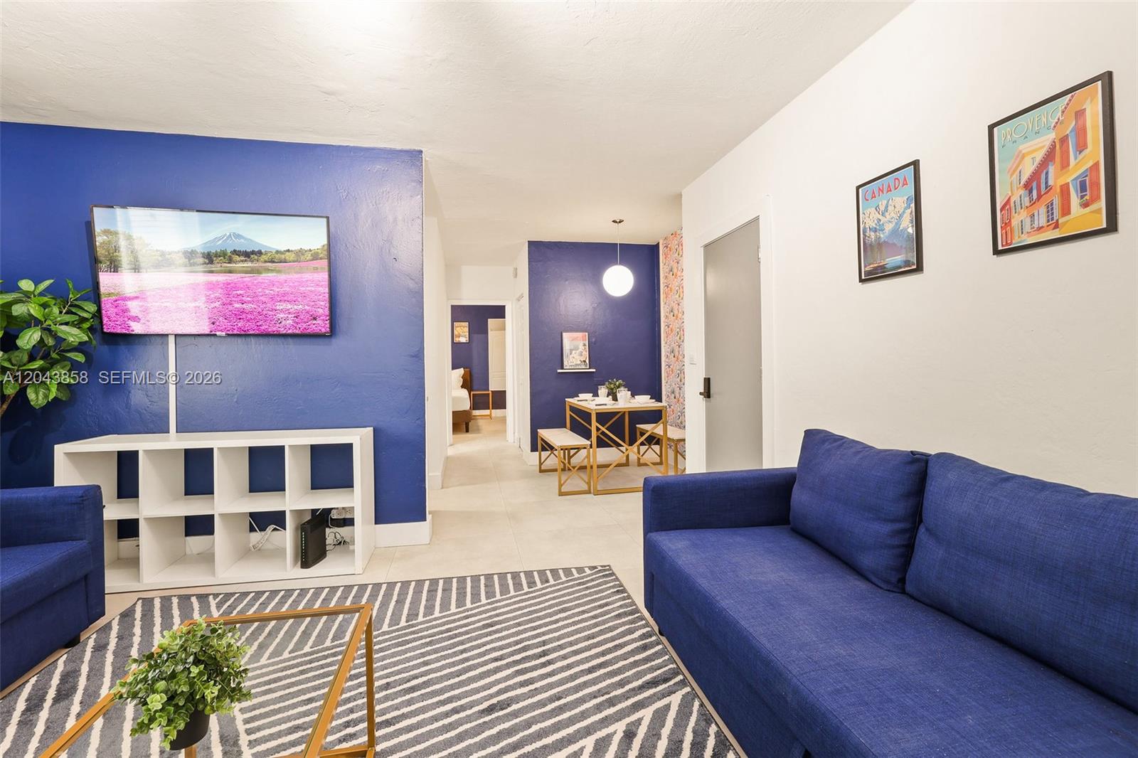 A living room features blue accent walls, a blue sofa, and a dining area — 7340 Harding Ave # 4, Miami Beach FL 33141, MIAMI BEACH, FL
