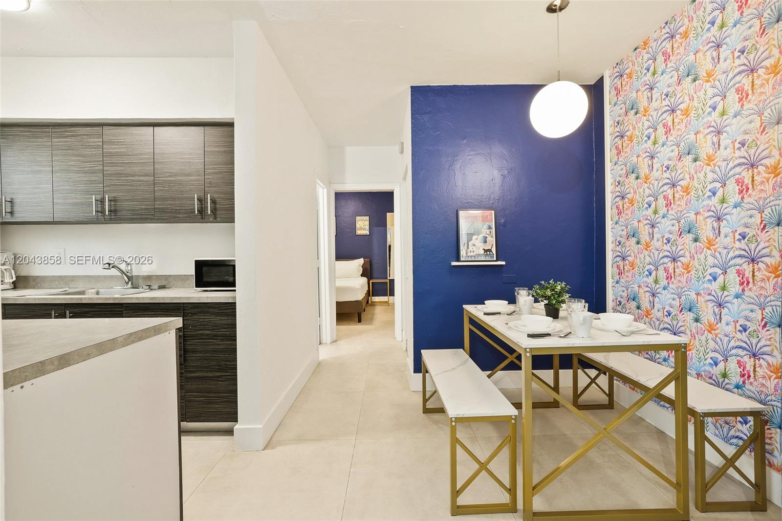A dining area with a patterned wallpaper wall sits adjacent to a modern kitchen — 7340 Harding Ave # 4, Miami Beach FL 33141, MIAMI BEACH, FL