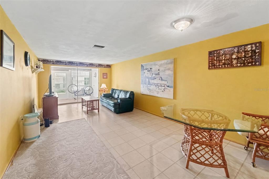A living and dining area features yellow walls, tile flooring, a dark sofa, and furniture — 4211 REGAL PLACE UNIT 3, NEW PORT RICHEY, FL