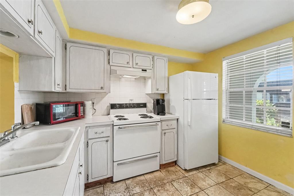 A kitchen with white cabinets, white appliances, yellow walls, and tiled flooring — 4211 REGAL PLACE UNIT 3, NEW PORT RICHEY, FL
