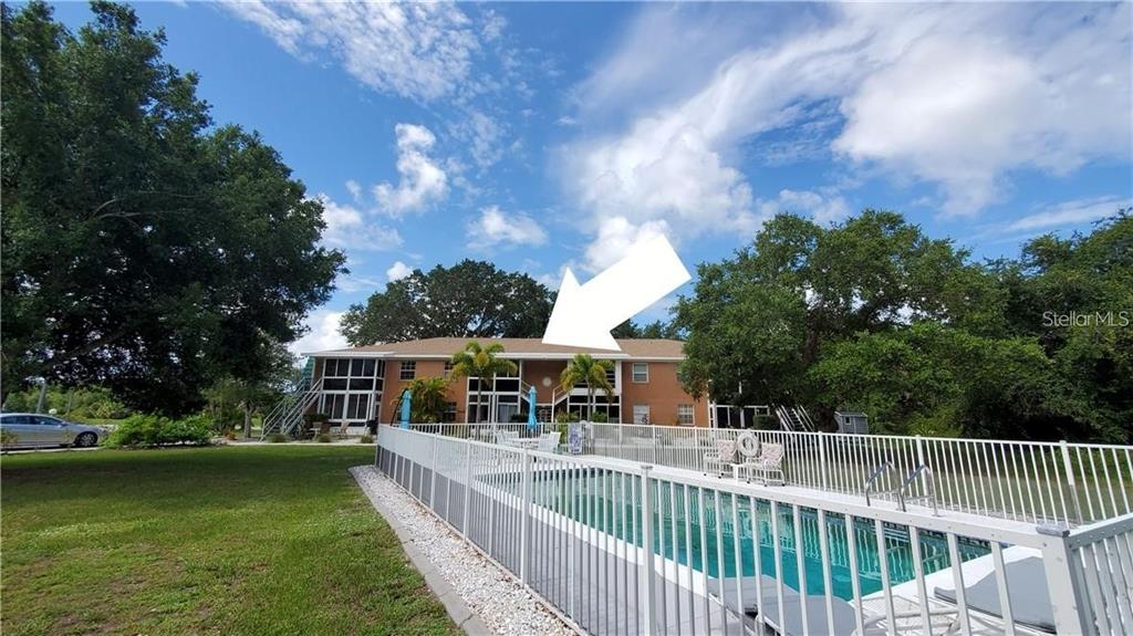 A two-story apartment building with a screened-in patio overlooks a fenced swimming pool — 3586 CAPE HAZE DRIVE UNIT B4, ROTONDA WEST, FL