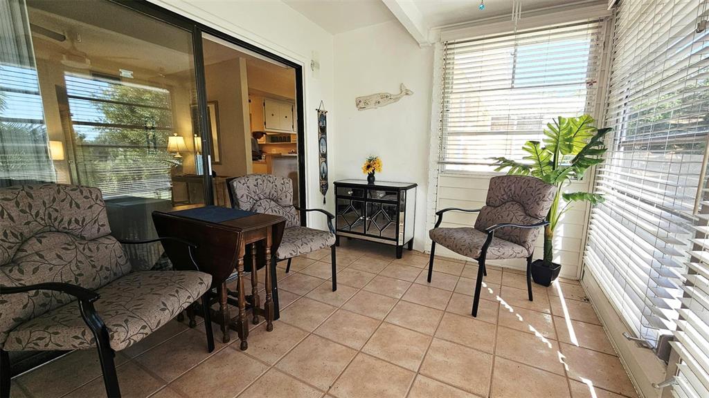 A sunroom features tiled floors, three patterned armchairs, a small wooden table, and mirrored furniture — 3586 CAPE HAZE DRIVE UNIT B4, ROTONDA WEST, FL