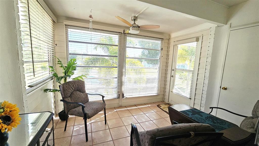 A sunroom features tile flooring, a ceiling fan, large windows with blinds, and patio furniture — 3586 CAPE HAZE DRIVE UNIT B4, ROTONDA WEST, FL
