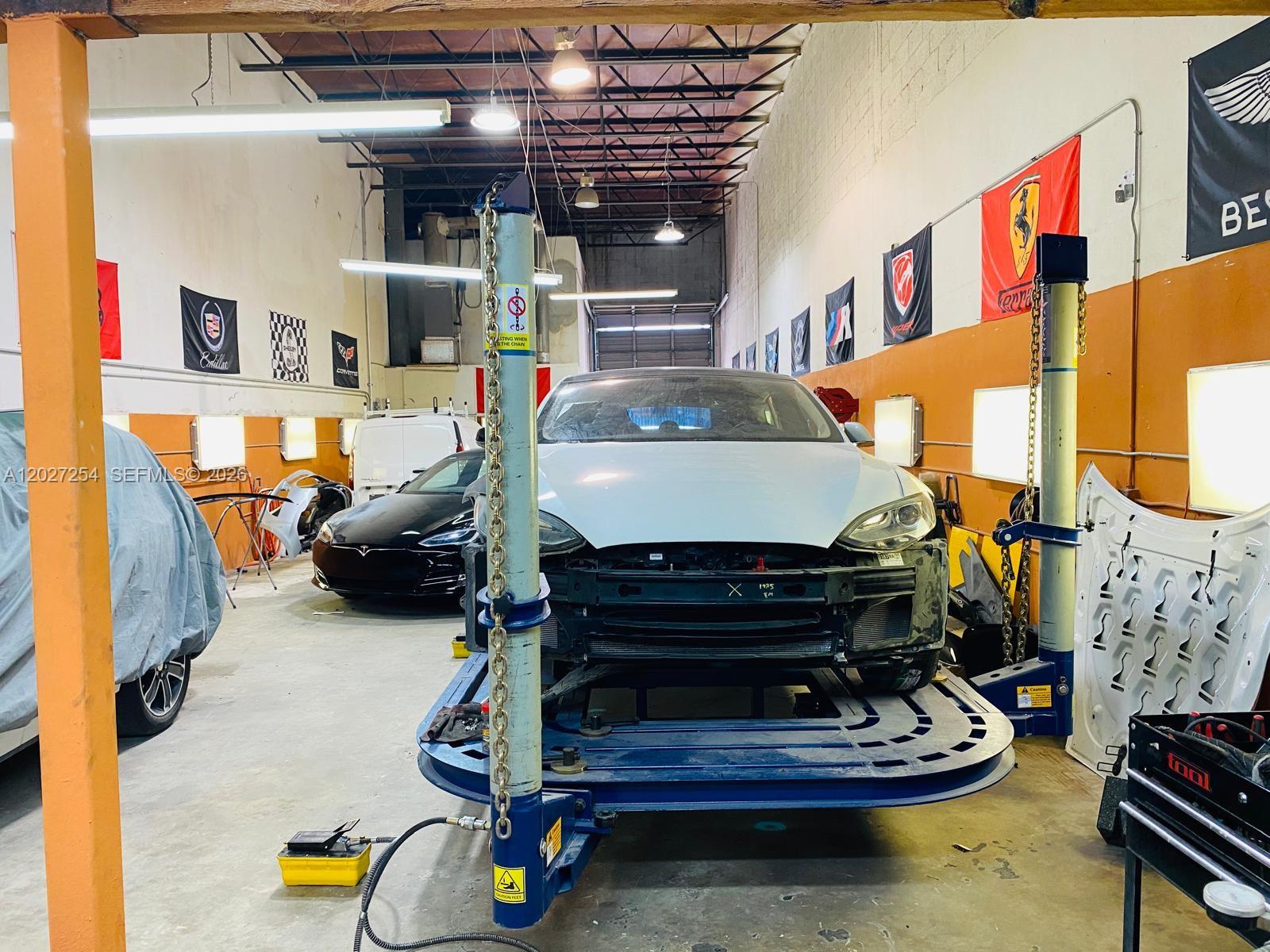 A car repair shop features a vehicle on a lift and various automotive wall banners — HIALEAH, FL