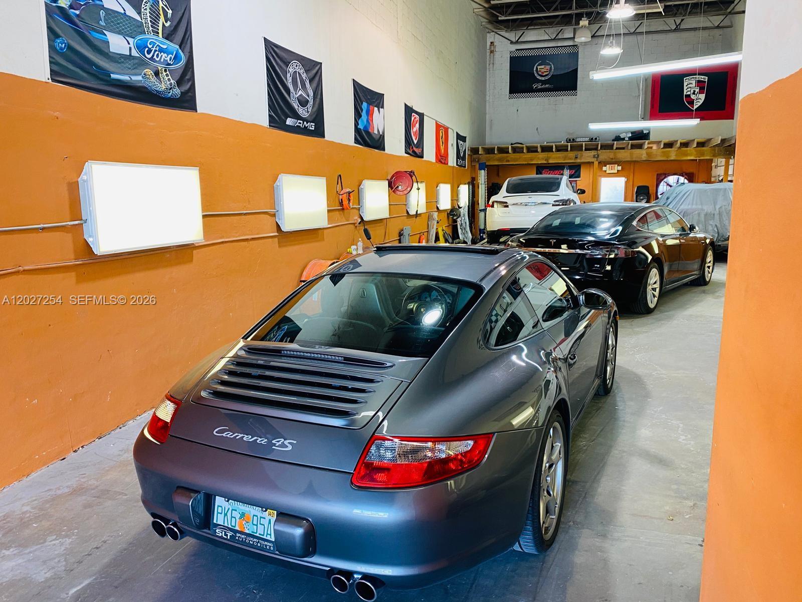 A garage features a gray Porsche Carrera 4S and other vehicles parked indoors — HIALEAH, FL