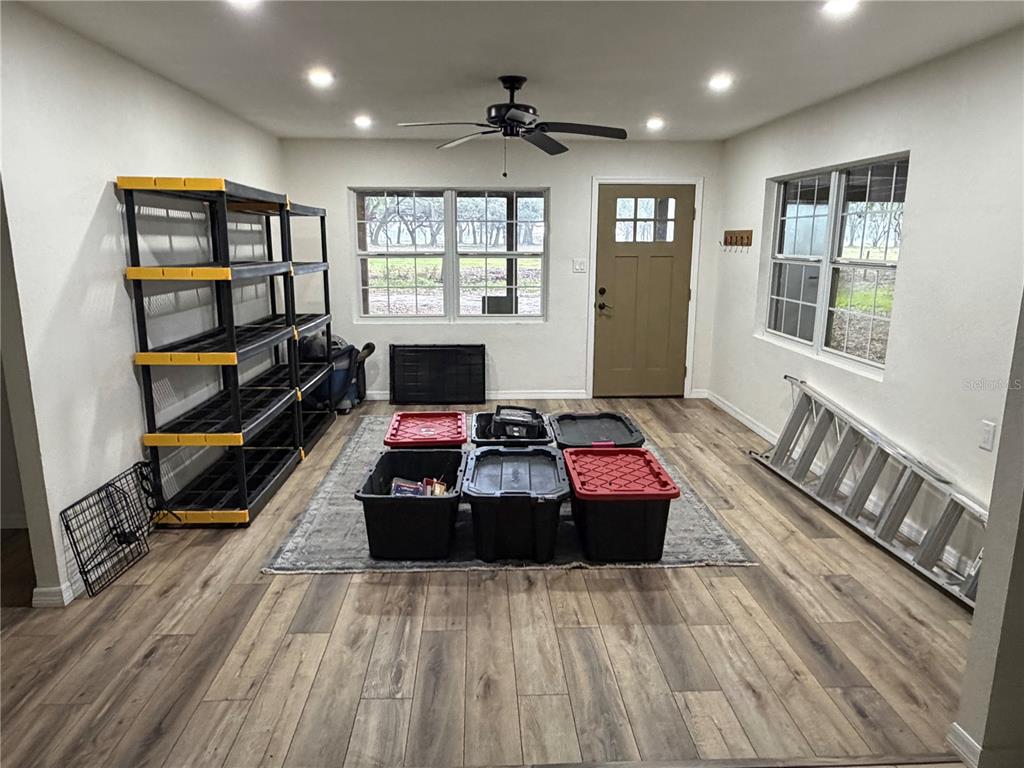 A room with wood-look flooring, a ceiling fan, storage shelves, and several plastic bins — 2748 CR 543, SUMTERVILLE, FL