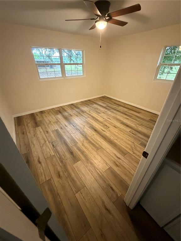 An empty bedroom features light-colored wood-look flooring, a ceiling fan, and two windows — 2748 CR 543, SUMTERVILLE, FL