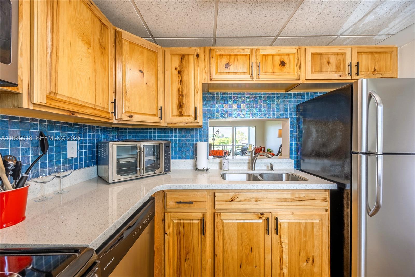 A kitchen features natural wood cabinets, blue mosaic tile backsplash, and a stainless steel refrigerator — OTHER CITY - IN THE STATE OF FLORIDA, FL