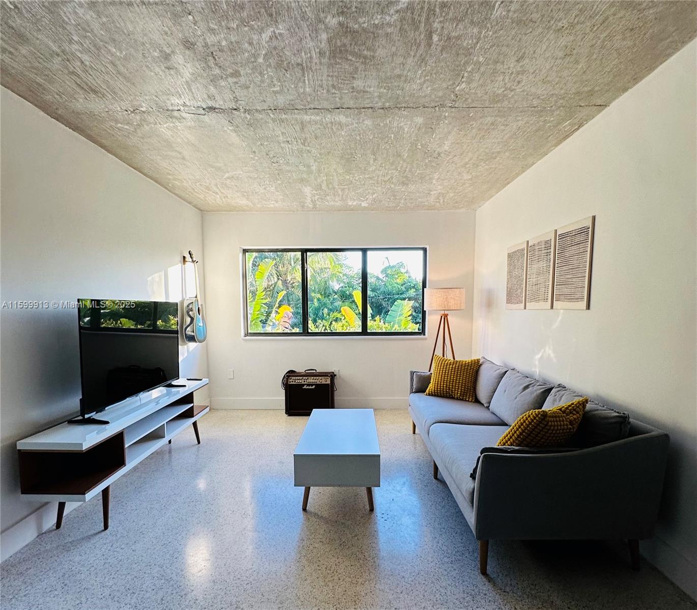 A living room features a grey sofa, white media console, and exposed concrete ceiling — 190 NW 69th St # 7, Miami FL 33150, MIAMI, FL