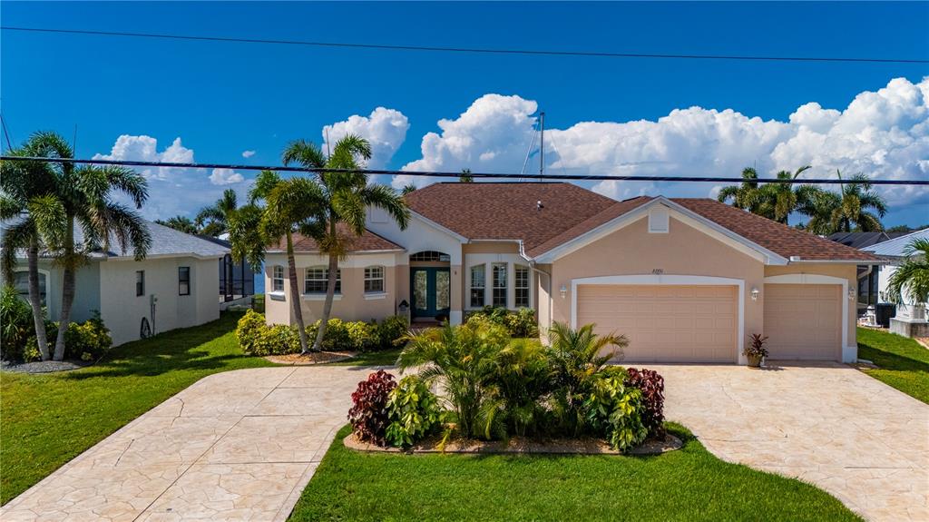 A tan, single-story house with a three-car garage and palm trees in the front yard — 21551 EDGEWATER DRIVE, PORT CHARLOTTE, FL