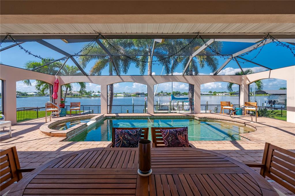 A covered patio features a swimming pool, outdoor furniture, and a view of a canal — 21551 EDGEWATER DRIVE, PORT CHARLOTTE, FL