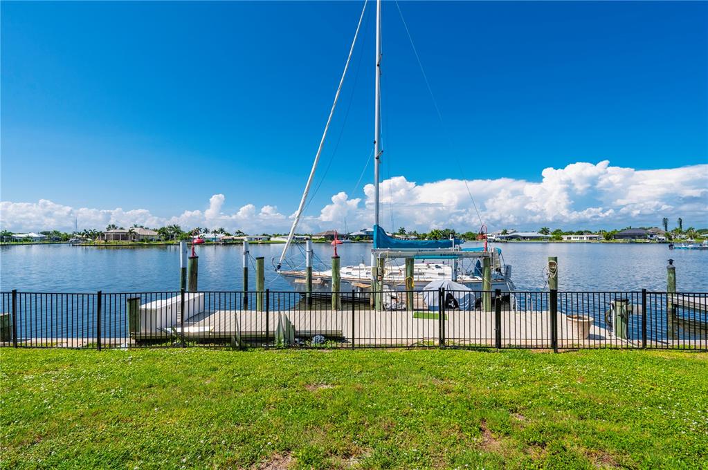 A sailboat is docked at a private pier behind a black metal fence near water — 21551 EDGEWATER DRIVE, PORT CHARLOTTE, FL