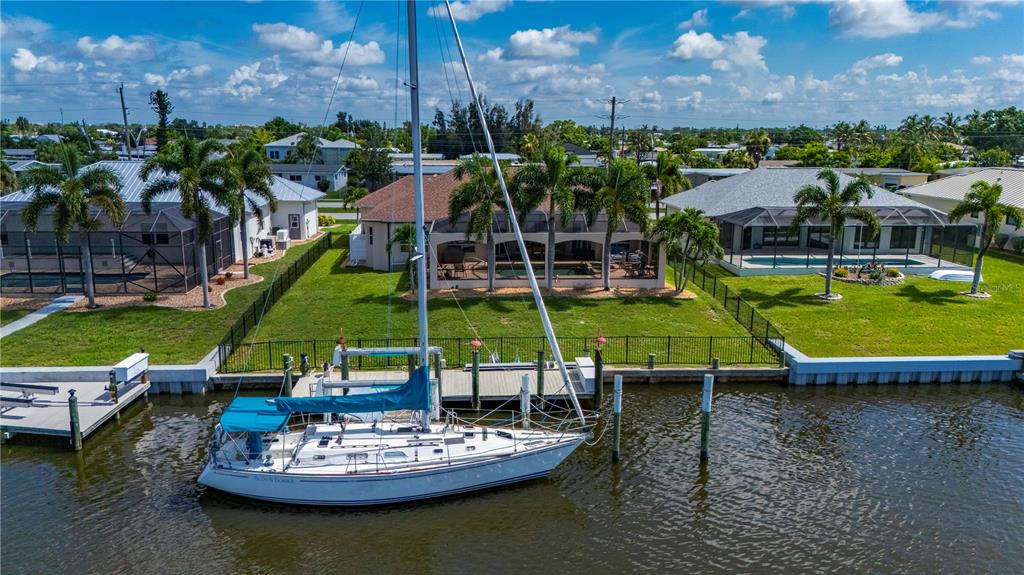 A sailboat is docked at a canal behind several houses with screened-in pools and lawns — 21551 EDGEWATER DRIVE, PORT CHARLOTTE, FL