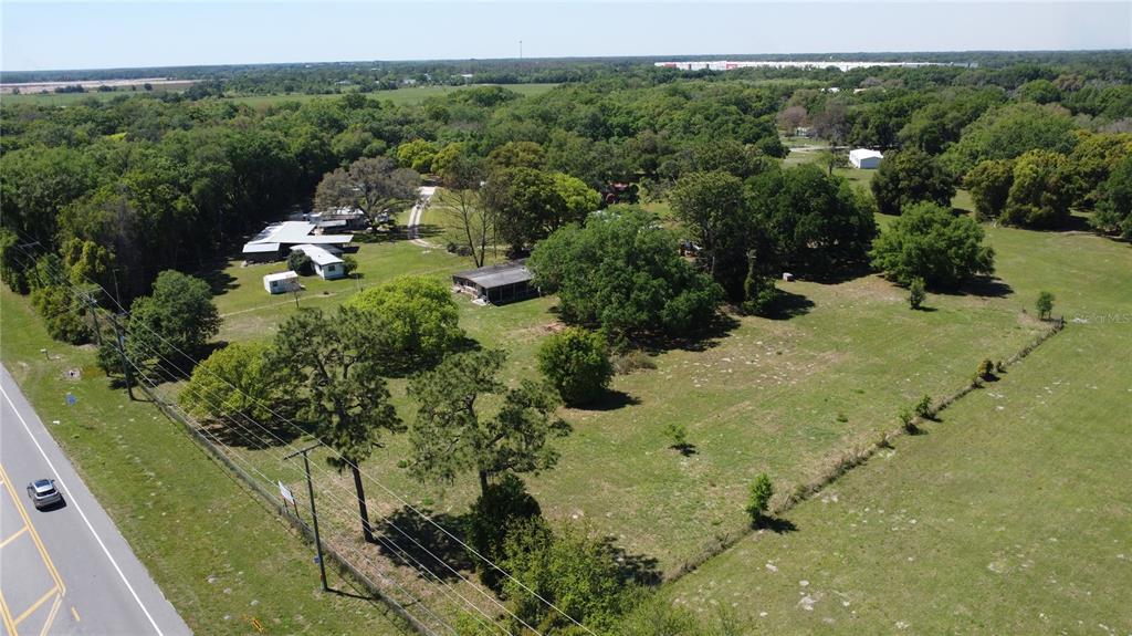 An aerial view shows a rural property with several buildings, trees, and a paved road — 31221 STATE ROAD 52, SAN ANTONIO, FL