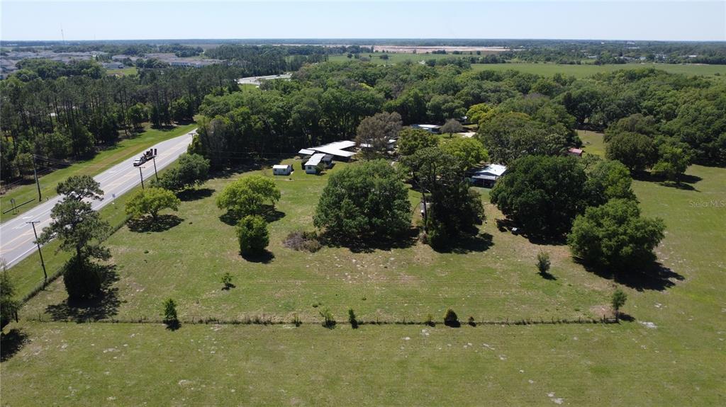 An aerial view shows a rural property with several buildings, scattered trees, and a fenced pasture — 31221 STATE ROAD 52, SAN ANTONIO, FL