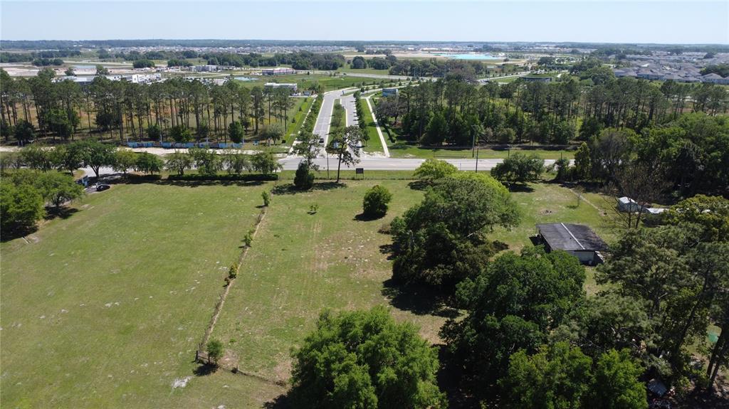 An aerial view shows a large, grassy lot with scattered trees and a small shed — 31221 STATE ROAD 52, SAN ANTONIO, FL