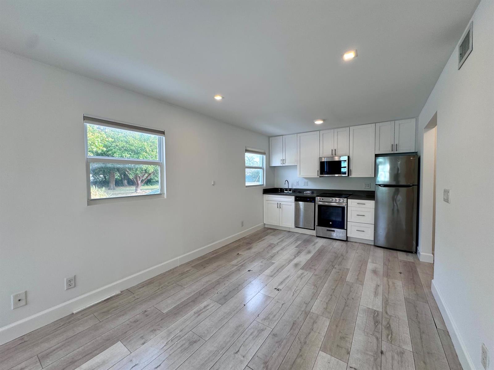 A kitchen with white cabinets, stainless steel appliances, and light wood-look flooring — 102 S K Street Unit 4, FL 33460, FL