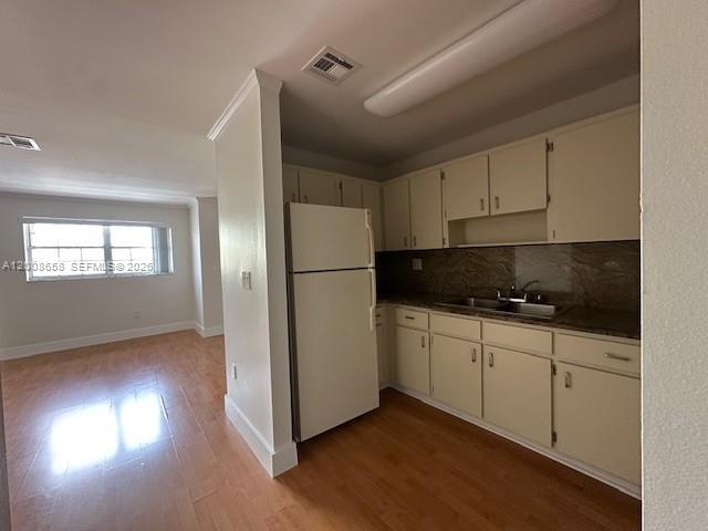 A kitchen with white cabinets and a refrigerator opens into a living area with flooring — 12990 SW 63rd Ter # 605, Miami FL 33183, MIAMI, FL