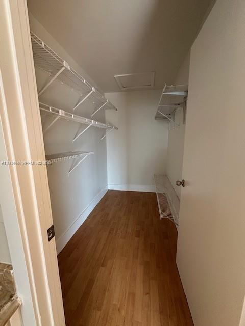 A walk-in closet features white wire shelving, light-colored walls, and wood-look flooring — 12990 SW 63rd Ter # 605, Miami FL 33183, MIAMI, FL