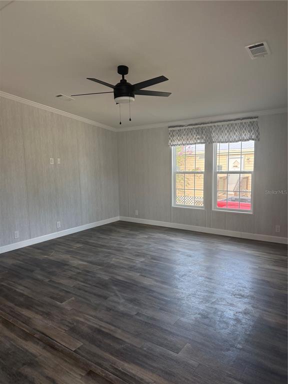 An empty room features wood-look flooring, light gray walls, a ceiling fan, and two windows — 10386 SE 52 COURT UNIT 12, BELLEVIEW, FL