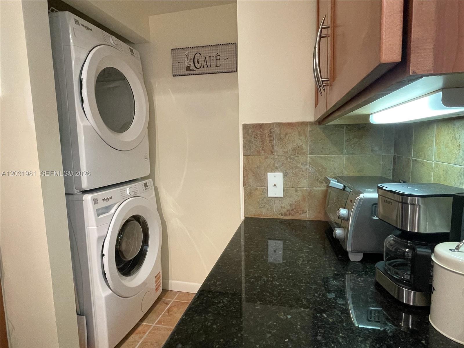 A stacked washer and dryer unit sits next to a kitchen counter with appliances — 2000 N Bayshore Dr # 525, Miami FL 33137, MIAMI, FL