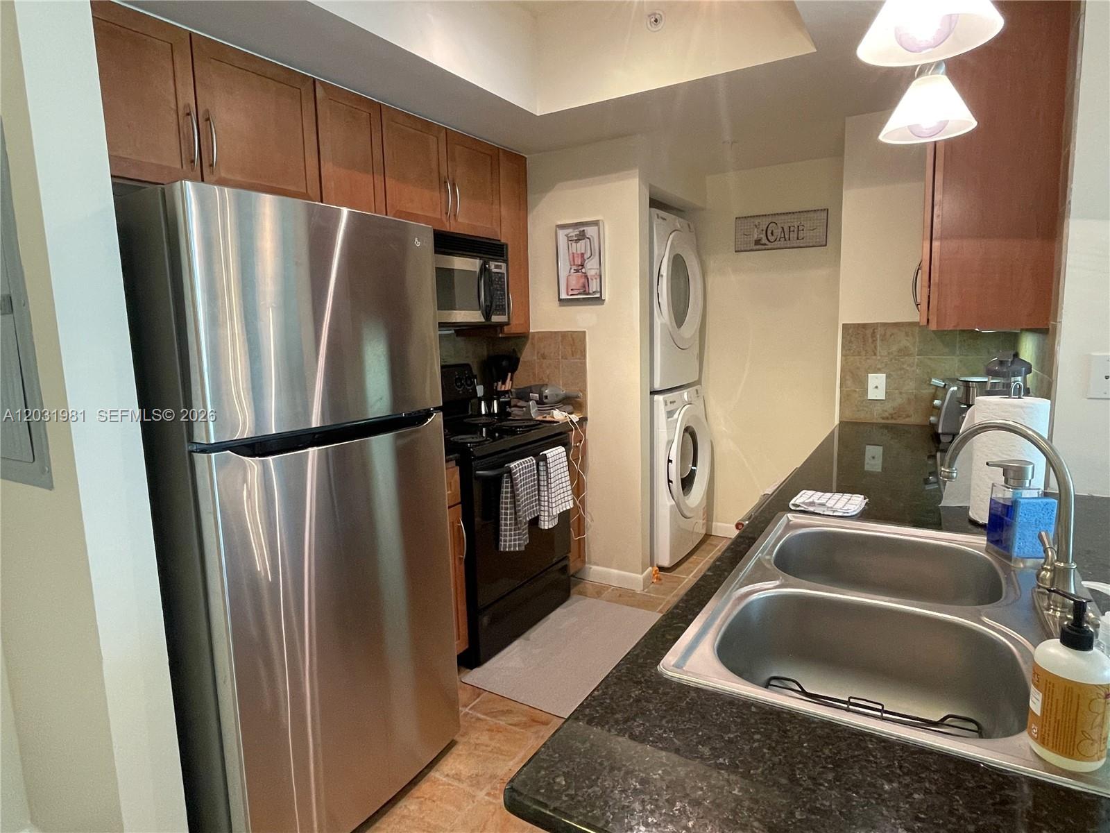 A kitchen features stainless steel appliances, dark granite countertops, and a stacked washer and dryer — 2000 N Bayshore Dr # 525, Miami FL 33137, MIAMI, FL