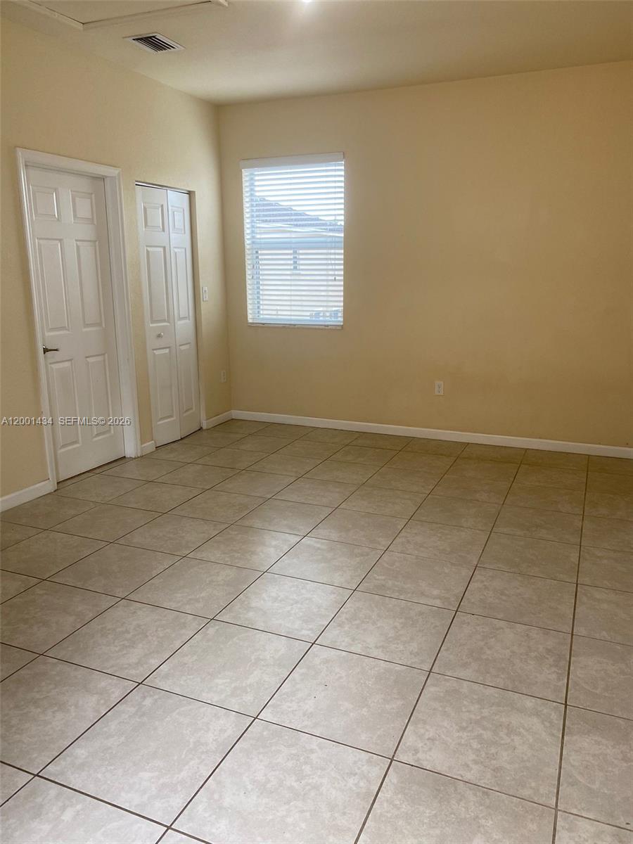 An empty room features beige walls, light-colored tile flooring, a window with blinds, and two doors — 17186 SW 93RD ST # 9410, Kendall FL 33196, KENDALL, FL