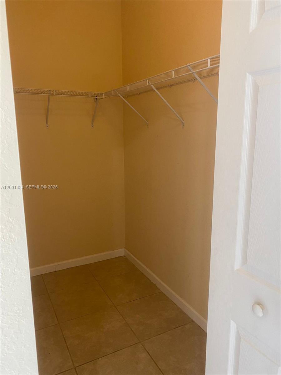 A walk-in closet features beige walls, tiled flooring, and white wire shelving — 17186 SW 93RD ST # 9410, Kendall FL 33196, KENDALL, FL