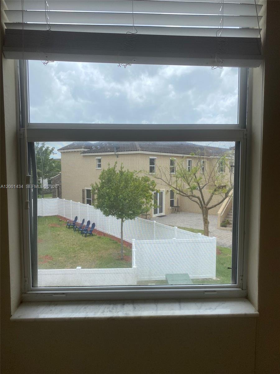 A view through a window shows a backyard with a white fence and patio — 17186 SW 93RD ST # 9410, Kendall FL 33196, KENDALL, FL