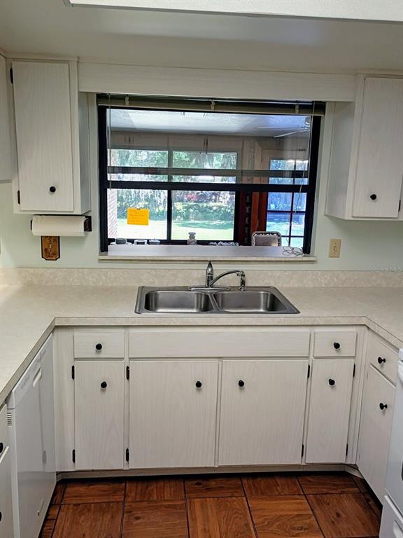 A kitchen features white cabinets, a double-basin sink, and a window overlooking a backyard — 4145 POLARIS AVENUE, TITUSVILLE, FL