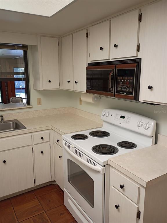 A kitchen features white cabinets, a white electric stove, and a brown over-the-range microwave — 4145 POLARIS AVENUE, TITUSVILLE, FL