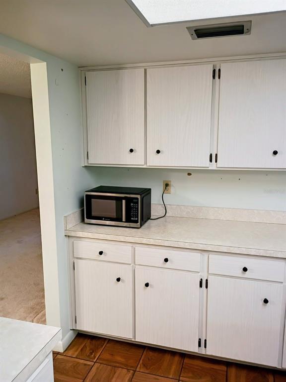 A kitchen features white cabinets, a countertop, and a microwave on a tiled floor — 4145 POLARIS AVENUE, TITUSVILLE, FL