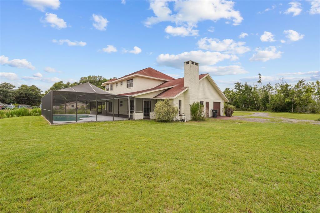 A two-story house with a screened-in pool and a large brick chimney sits on grass — 3101 LAKE LOWERY ROAD, HAINES CITY, FL