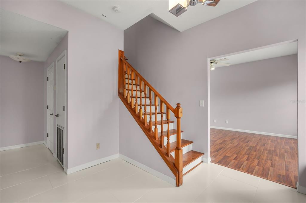 A staircase with wooden railings and steps stands in a room with light-colored tile flooring — 3101 LAKE LOWERY ROAD, HAINES CITY, FL