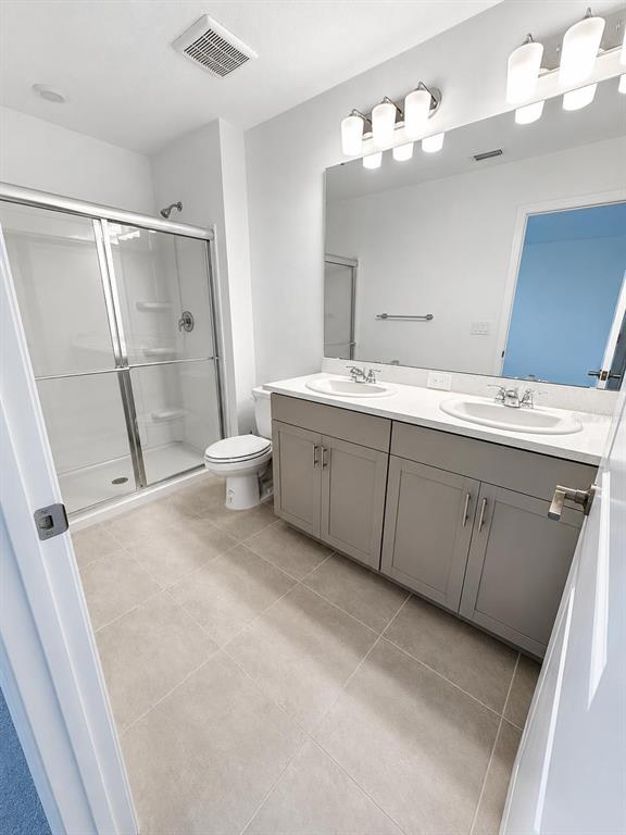 A bathroom features a double vanity with grey cabinets, a walk-in shower, and tile flooring — 8749 WINTER BREEZE WAY, SARASOTA, FL