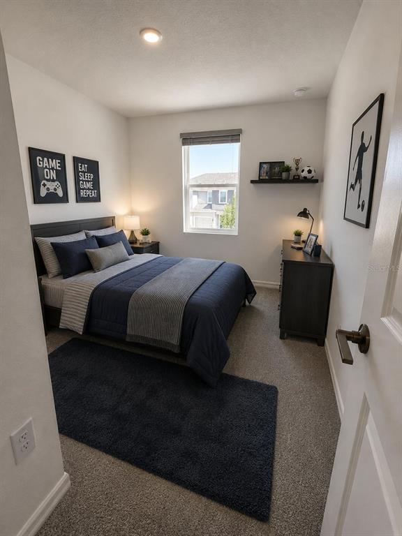 A bedroom with a bed, dresser, window, and blue rug on carpeted flooring — 8749 WINTER BREEZE WAY, SARASOTA, FL